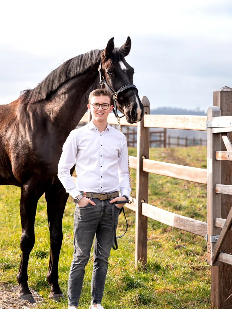 Luis Tillman mit einem schwarzen Pferd am Koppelzaun
